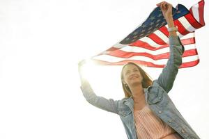 A girl in a coral dress and a denim jacket holds the flag of usa photo