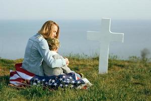 Mom and son are sitting on the grave of a soldier