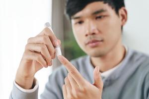 Man use lancet on finger checking blood sugar level by Glucose meter. photo