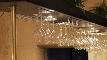 Empty Wine Glasses Hanging on Wooden Shelf Above a Bar video