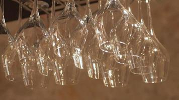 Rows of Empty Wine Glasses Hanging on Wooden Shelf Above a Bar video