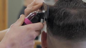 In der Nähe des Mannes, der sich im Friseursalon die Haare schneidet. männlicher Friseur bei der Arbeit. video