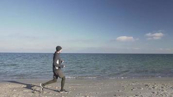 joven corredor de entrenamiento en la playa por la mañana video