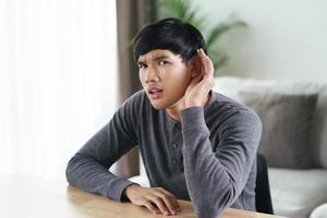 Deaf disabled man having hearing problems holds his hand over the ear. photo