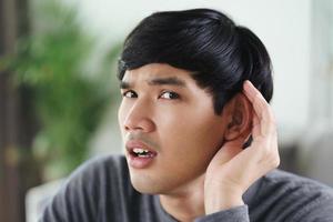 Deaf disabled man having hearing problems holds his hand over the ear. photo