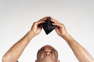 man holding upside down and looking inside his empty wallet. photo