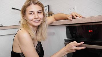 Mujer cocinando en la cocina abriendo la puerta del horno. foto