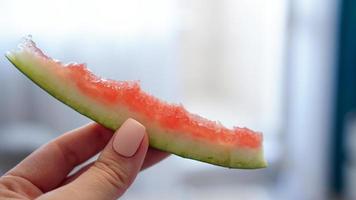 Hand holding eaten slice of watermelon on blurred background photo