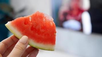 Slice of watermelon in hand on a blurred background photo