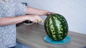 Closeup of woman hand cutting watermelon in the kitchen photo