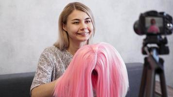 Woman blogger records video. She shows pink wig
