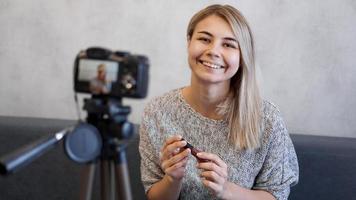 mujer vlogger mostrando lápiz labial. blogger de belleza en estudio casero foto