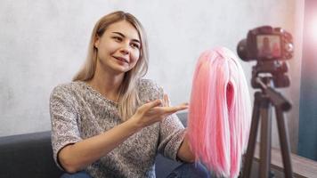 Woman blogger records video. She shows pink wig photo