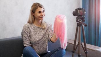 Woman blogger records video. She shows pink wig photo