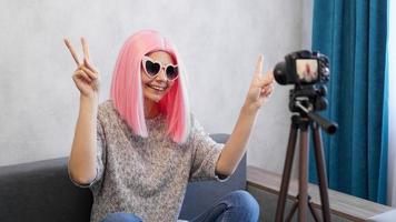 Happy teen girl blogger in pink wigs and glasses photo