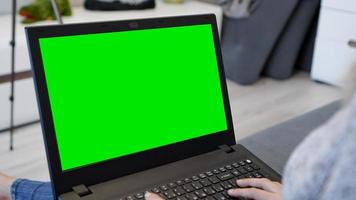 Woman using laptop with green screen. Woman typing photo
