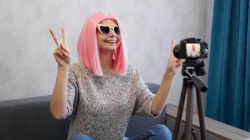 Happy teen girl blogger in pink wig and glasses photo