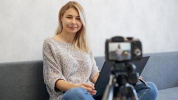 Young female blogger with laptop looking at camera photo