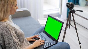 View of camera on tripod and laptop with green screen chromakey photo