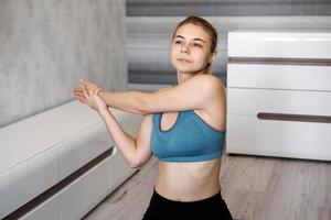 Smiling girl streching on floor at home. Stretching the arms photo