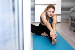 Sport, training and lifestyle concept - woman stretching leg on mat photo