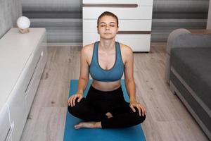 Yoga at home. Keep calm. Attractive young woman sitting photo
