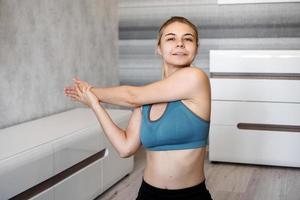 Smiling girl streching on floor at home. Stretching the arms photo