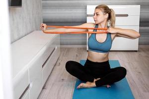 Woman at home trying to lose weight and training with elastic band photo