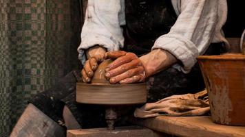 Manos de alfarero haciendo en arcilla en torno de alfarería foto