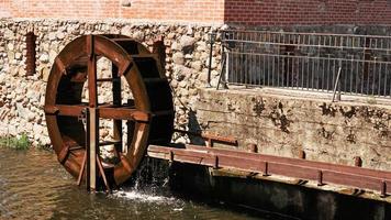 An old water mill on the background of a brick building. photo