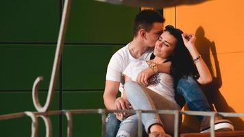 Couple kissing against isolated yellow and green wall in the city photo
