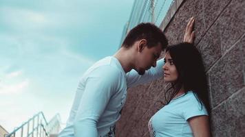 Young loving couples standing next to the brick wall photo