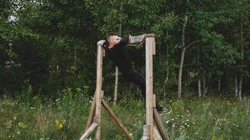 El hombre atravesando obstáculos durante la carrera de obstáculos en el campo de entrenamiento foto