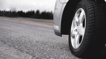 Wheel of silver car on the road. Photo in gray tones