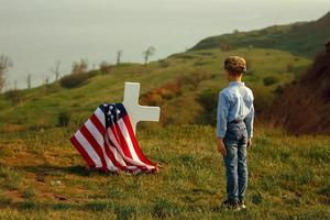 Young boy in a military cap salutes his father's grave photo