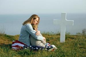 Mom and son are sitting on the grave of a soldier