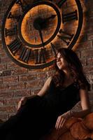 Young attractive woman under the clock, on brick wall background photo