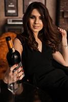 Pretty young sexy woman with long hair holding wine bottle photo