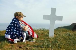 Young boy in a military cap at his father's grave on memorial day photo