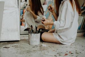 mujer pintora sentada en el suelo frente al espejo. estudio de arte foto