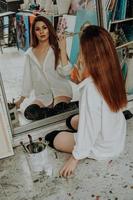 mujer pintora sentada en el suelo frente al espejo. estudio de arte foto