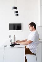 Young smiling man working with laptop from home photo