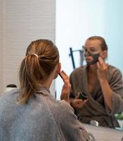 Mujer aplicando mascarilla en el baño. foto