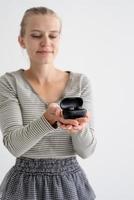 Young woman holding wireless earbuds photo