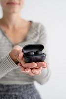 Young woman holding wireless earbuds photo