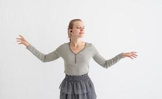 Young woman holding wireless earbuds and dancing photo