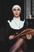 hermosa joven monja en religión traje negro tiene Biblia. religión foto