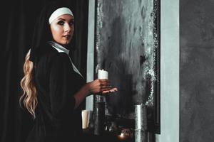 joven monja católica sostiene una vela en sus manos