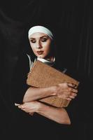Beautiful young nun in religion black suit holds Bible. Religion