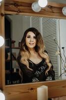 Beautiful young woman looking at her reflection in a dressing mirror photo